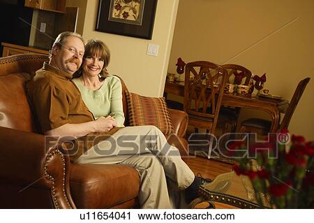 Couple sitting on sofa View Large Photo Image Stock Image - Couple sitting on sofa. Fotosearch