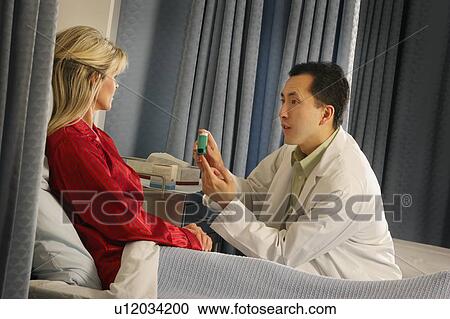 Stock Image - Doctor instructing patient with inhaler. Fotosearch