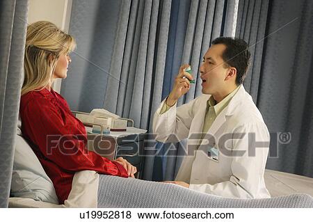 Doctor instructing patient with inhaler View Large Photo Image Stock Photo - Doctor instructing patient with inhaler. Fotosearch