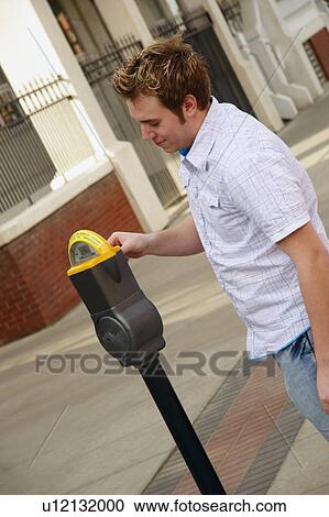 Stock Image - Man plugging a parking meter. Fotosearch