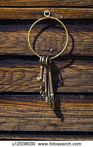 Stock Image - Old-fashioned keys hanging on log wall. Fotosearch