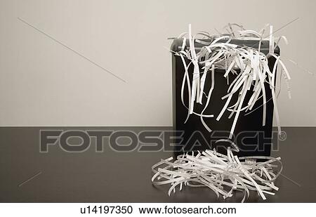 Stock Image - Overflowing garbage can with shredded paper. Fotosearch