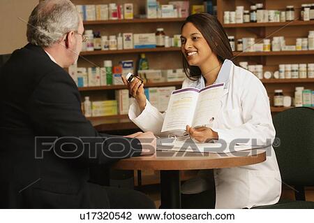 Stock Image - Pharmacist consulting patient. Fotosearch