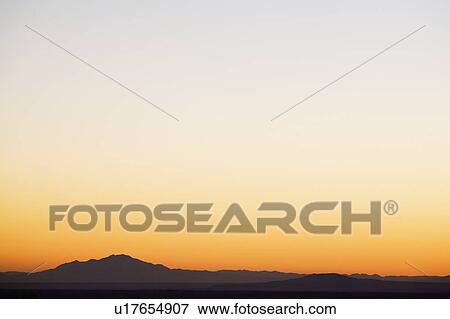 Stock Photo - Sunset sky over silhouetted mountains. Fotosearch