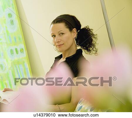Stock Image - Woman behind blurred flowers. Fotosearch