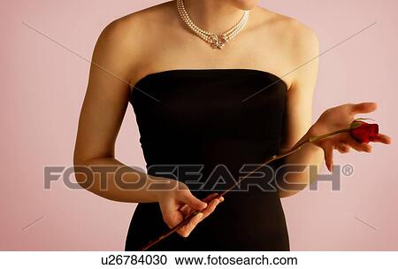 Stock Image - Woman holding a single rose. Fotosearch