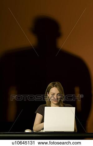 Stock Image - Woman On Computer with Menacing Shadow. Fotosearch