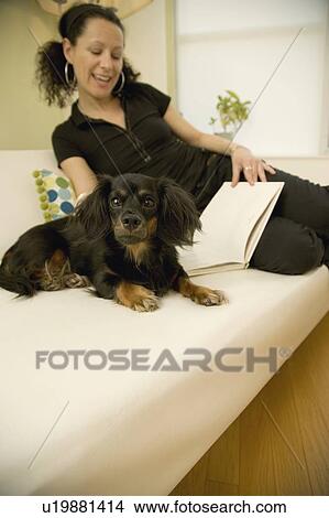 Picture - Woman reading at home with dog. Fotosearch