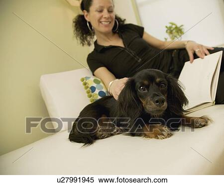 Stock Photography - Woman reading with dog. Fotosearch