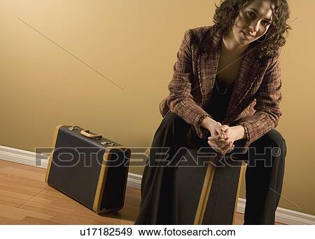 Stock Photo - Woman sitting on suitcase. Fotosearch