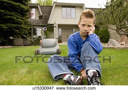 A boy sulks and avoids mowing the lawn View Large Photo Image Stock Photo - A boy sulks and avoids mowing the lawn. Fotosearch