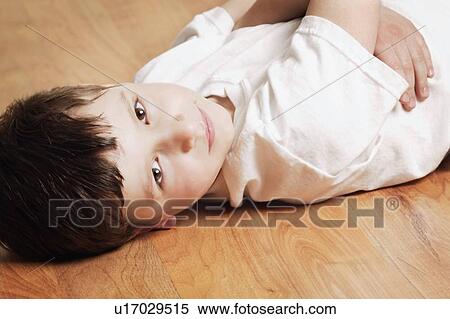 Stock Photography - Boy laying on hardwood floor. Fotosearch
