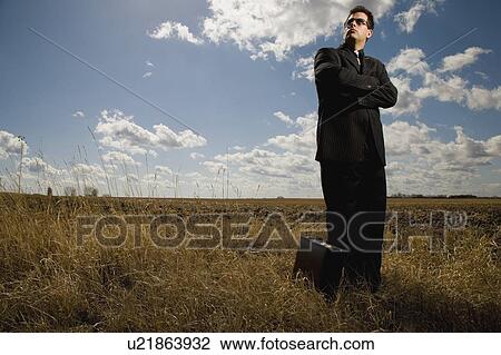 Stock Image - Business man in farmers field. Fotosearch