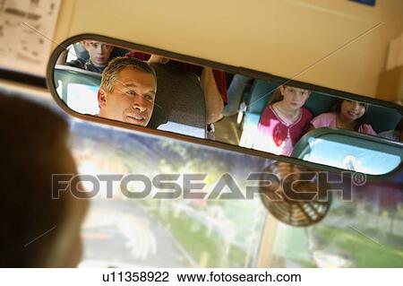 Stock Image - Children in school bus through drivers mirror. Fotosearch