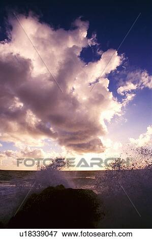 Stock Photo - Clouds and wave spray over rocks . Fotosearch