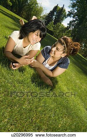 Stock Photography - Girls laughing in grass. Fotosearch
