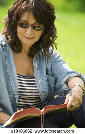 Stock Image - Lady reading in the park. Fotosearch