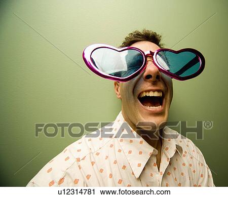 Stock Image - Man wearing large, heart-shaped glasses. Fotosearch