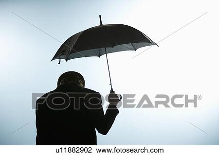 Stock Image - Person with head down holding umbrella. Fotosearch