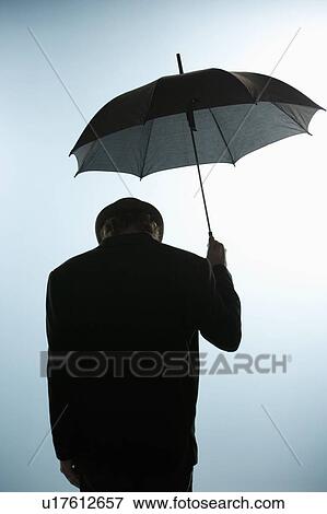 Stock Photo - Person with head down holding umbrella. Fotosearch