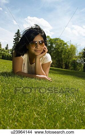 Picture - Young woman lying on grass. Fotosearch