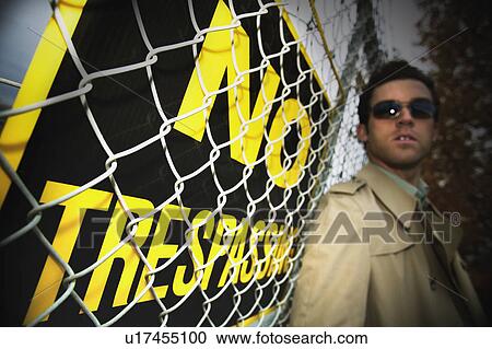 Stock Image - A man beside a no trespassing sign. Fotosearch