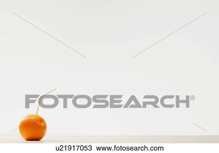 Stock Image - An orange with a straw. Fotosearch
