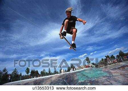 Boarder performing stunt at skate park View Large Photo Image Stock Image - Boarder performing stunt at skate park. Fotosearch