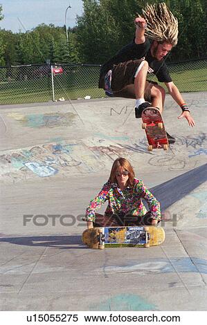 Boarders performing stunt at skate park View Large Photo Image Stock Photography - Boarders performing stunt at skate park. Fotosearch