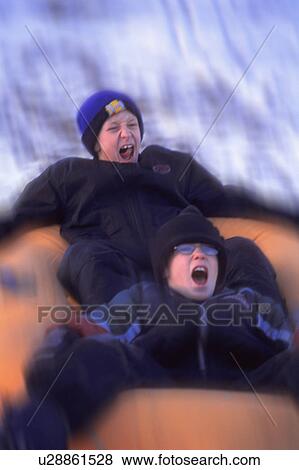 Stock Photo - Boys sliding down a hill on a raft. Fotosearch