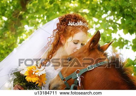 Stock Image - Bride kisses a horse. Fotosearch