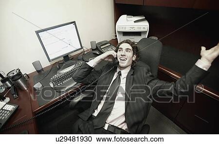 Stock Image - Businessman in office talking on phone. Fotosearch