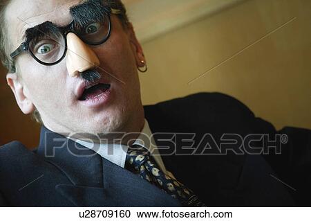Stock Image - Businessman looking surprised wearing Groucho Marx disguise. Fotosearch