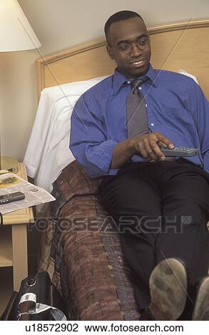 Businessman watching television in hotel room View Large Photo Image Stock Image - Businessman watching television in hotel room. Fotosearch
