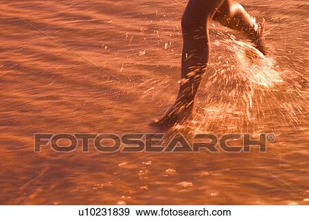 Stock Photo - Child Running through water on beach . Fotosearch