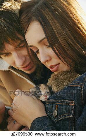 Stock Image - Couple cuddle a kitten. Fotosearch