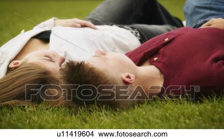 Picture - Couple lying face up on grass. Fotosearch