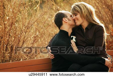 Stock Image - Couple share a bench. Fotosearch