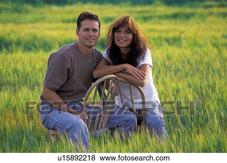 Couple sitting in a field View Large Photo Image Stock Photo - Couple sitting in a field. Fotosearch