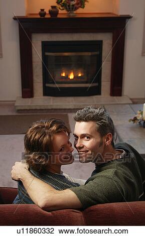 Stock Image - Couple snuggles by fire. Fotosearch