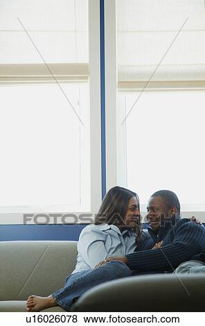 Stock Photo - Couple snuggles on sofa. Fotosearch