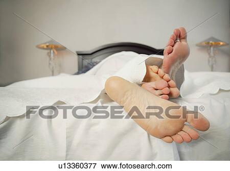 Stock Photo - Couple snuggles under sheets. Fotosearch