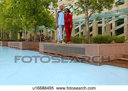 Stock Photography - Couple takes a walk beside a pool. Fotosearch