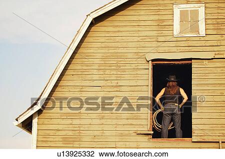Stock Image - Cowgirl in barn. Fotosearch