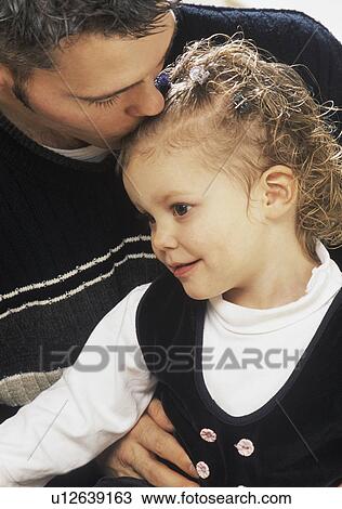 Stock Image - Father kissing daughter on the head. Fotosearch
