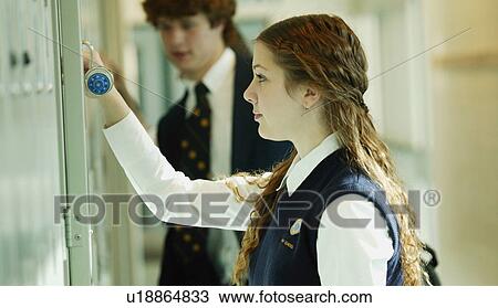 Stock Image - Female student opening locker. Fotosearch