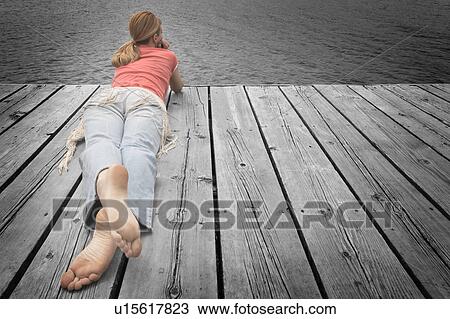 Stock Image - Girl laying on decking. Fotosearch