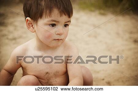 Stock Image - Little boy sitting on beach. Fotosearch