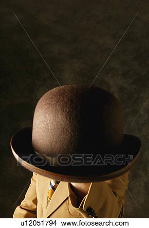 Man holds a hat in front of face View Large Photo Image Picture - Man holds a hat in front of face. Fotosearch