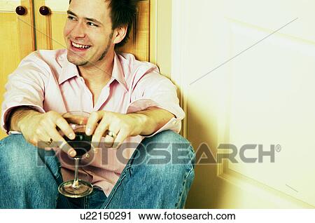 Stock Image - Man smiles while holding wine. Fotosearch